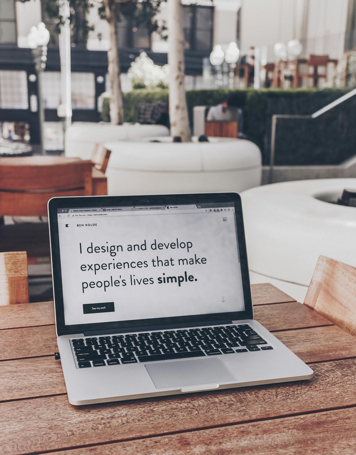 A laptop displaying a design portfolio in a cafe.