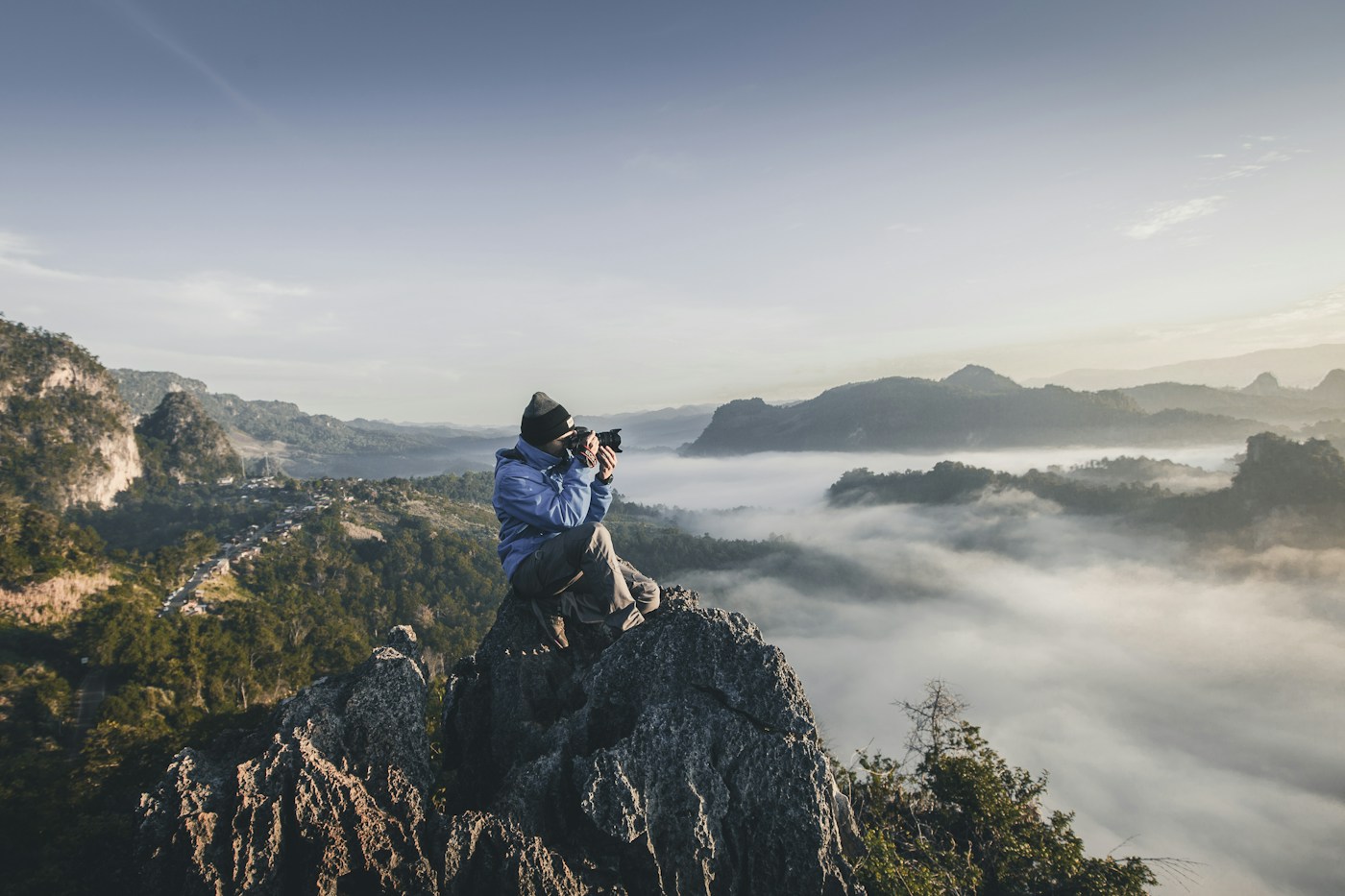 A photographer working above a misty mountain landscape.